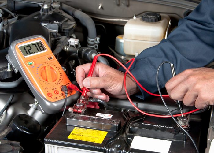 Auto mechanic checking car battery voltage